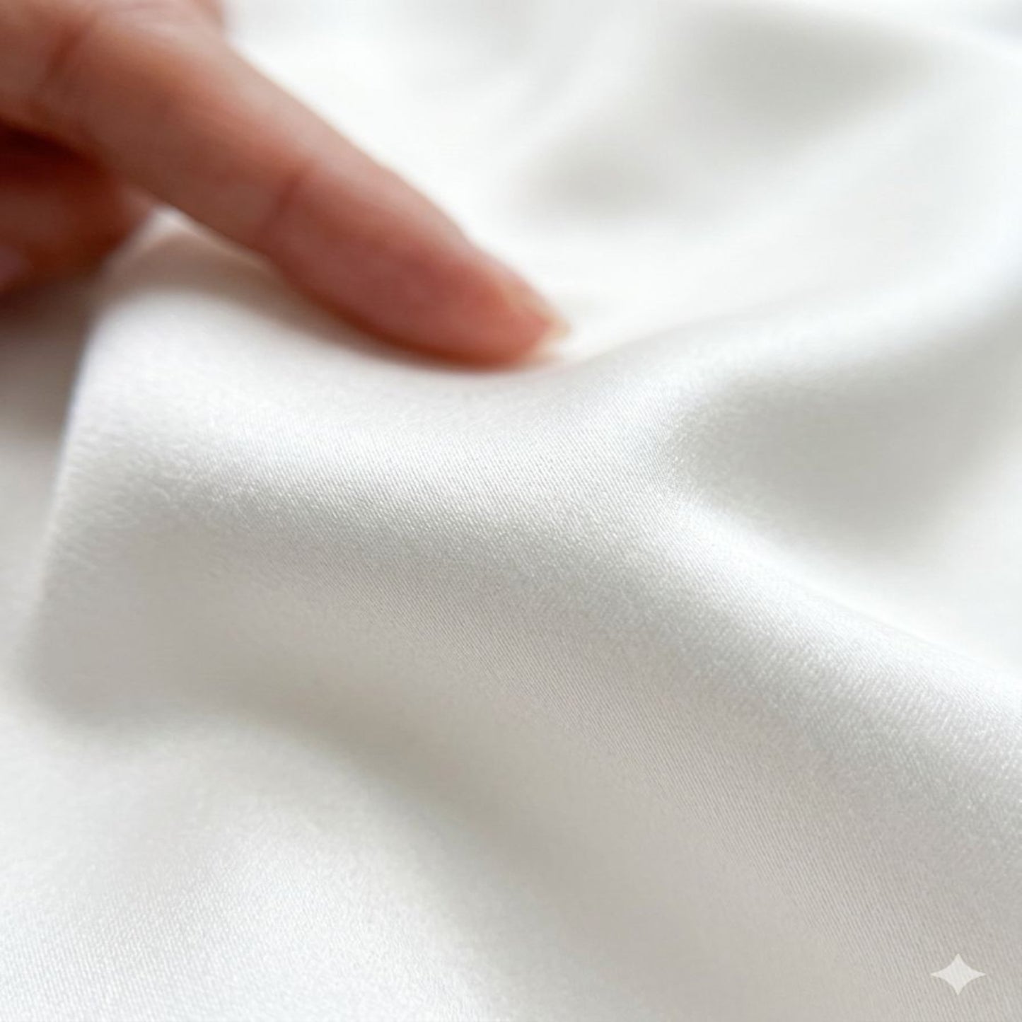 Close-up of a hand touching soft white fabric